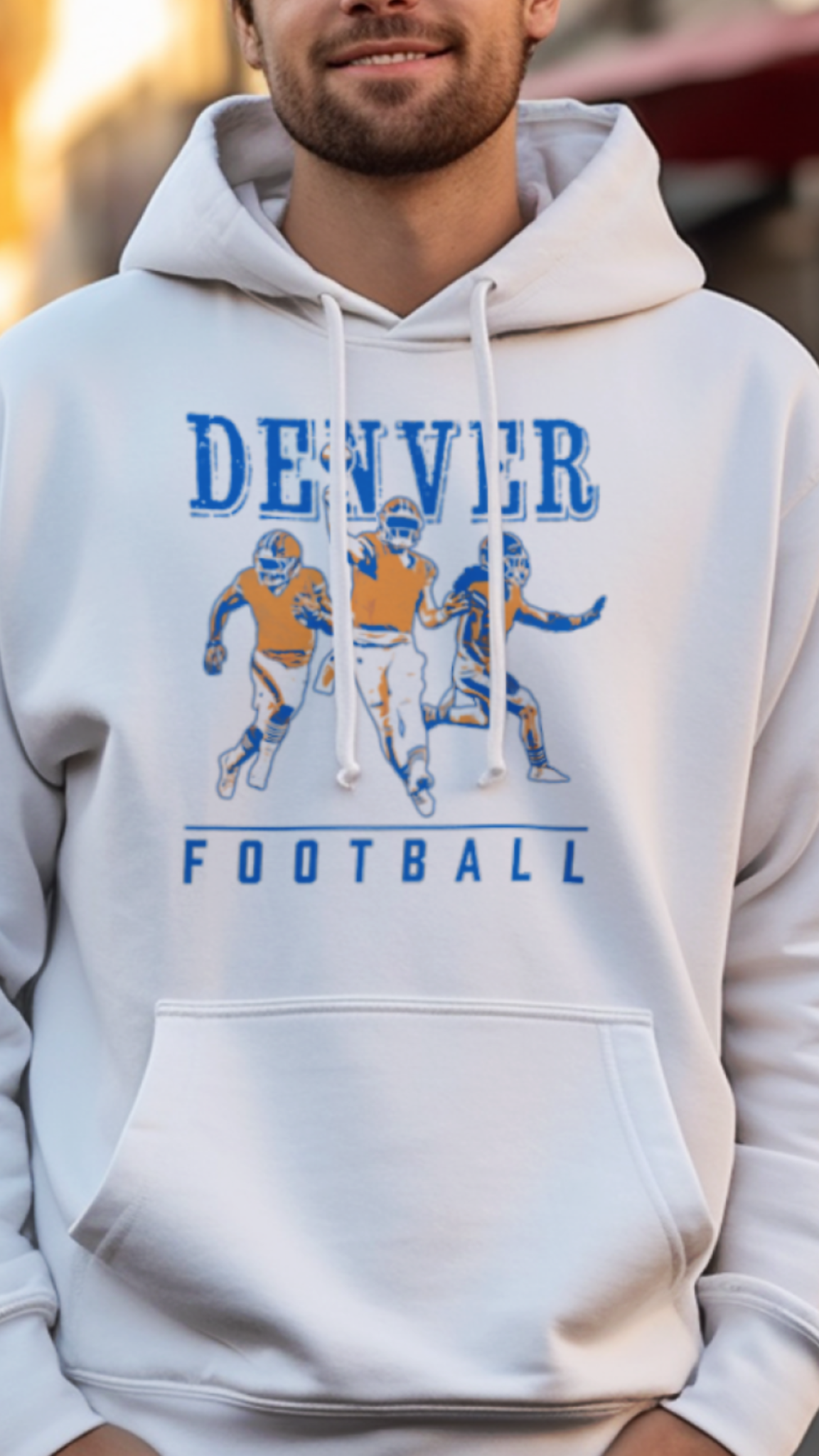 Man wearing a 'Denver Football' hoodie on a street with buildings in the background