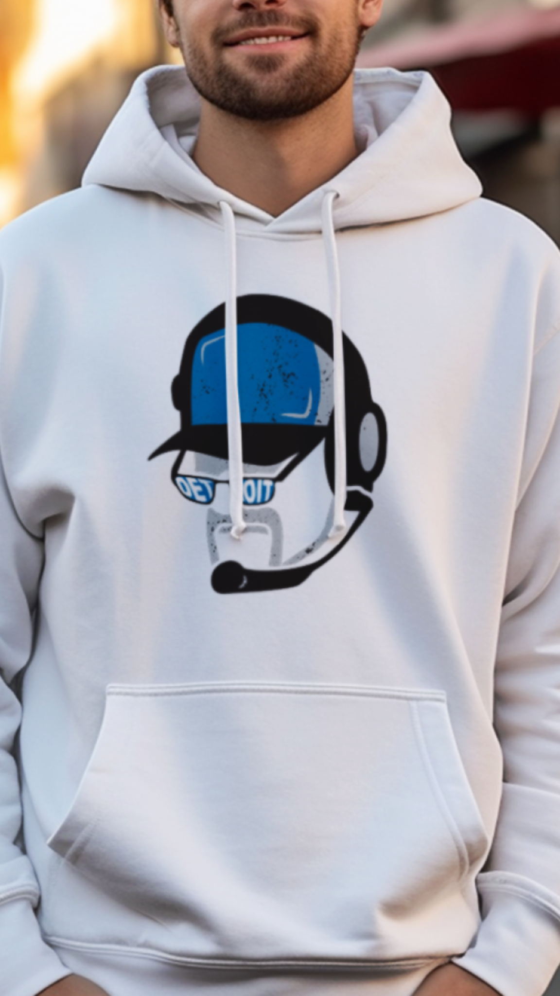 Man wearing a white hoodie with a graphic design on a street background
