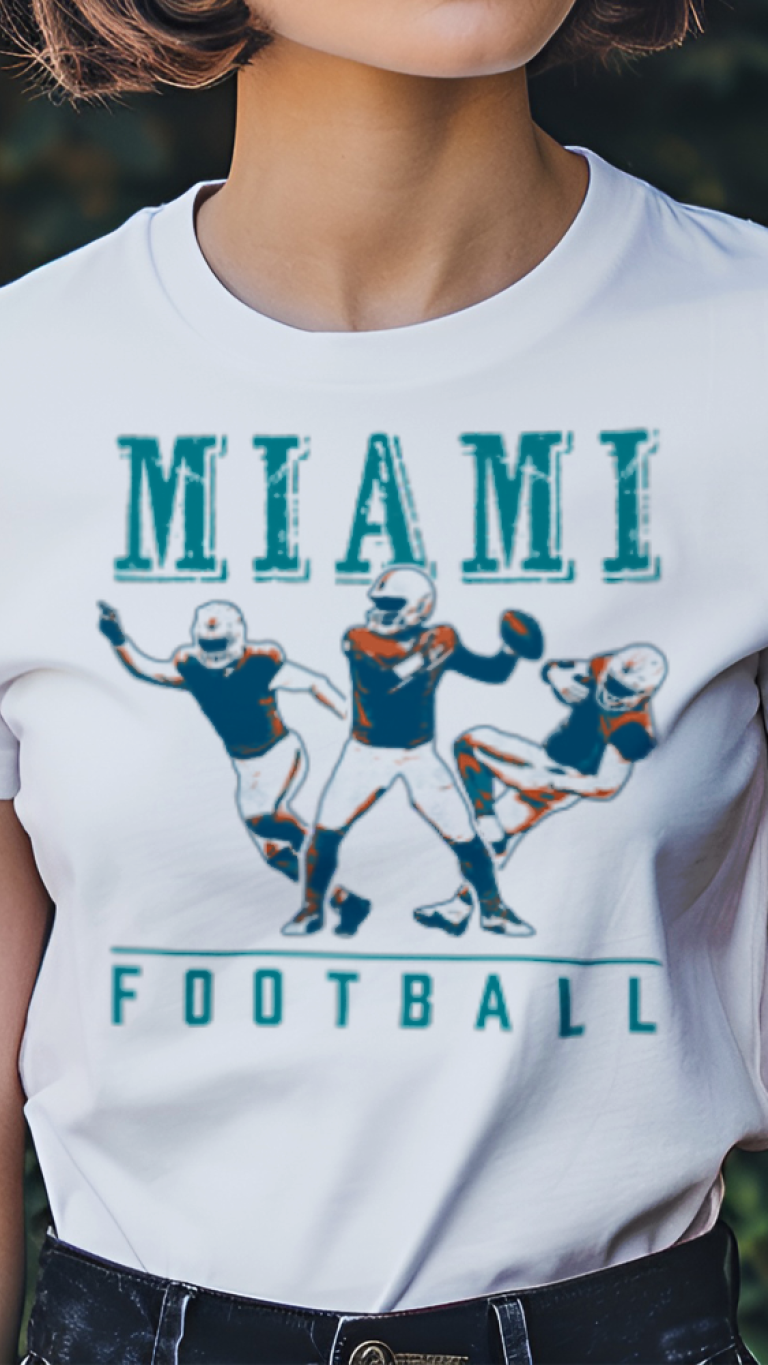 Person wearing a white t-shirt with 'Miami Football' graphic design outdoors.
