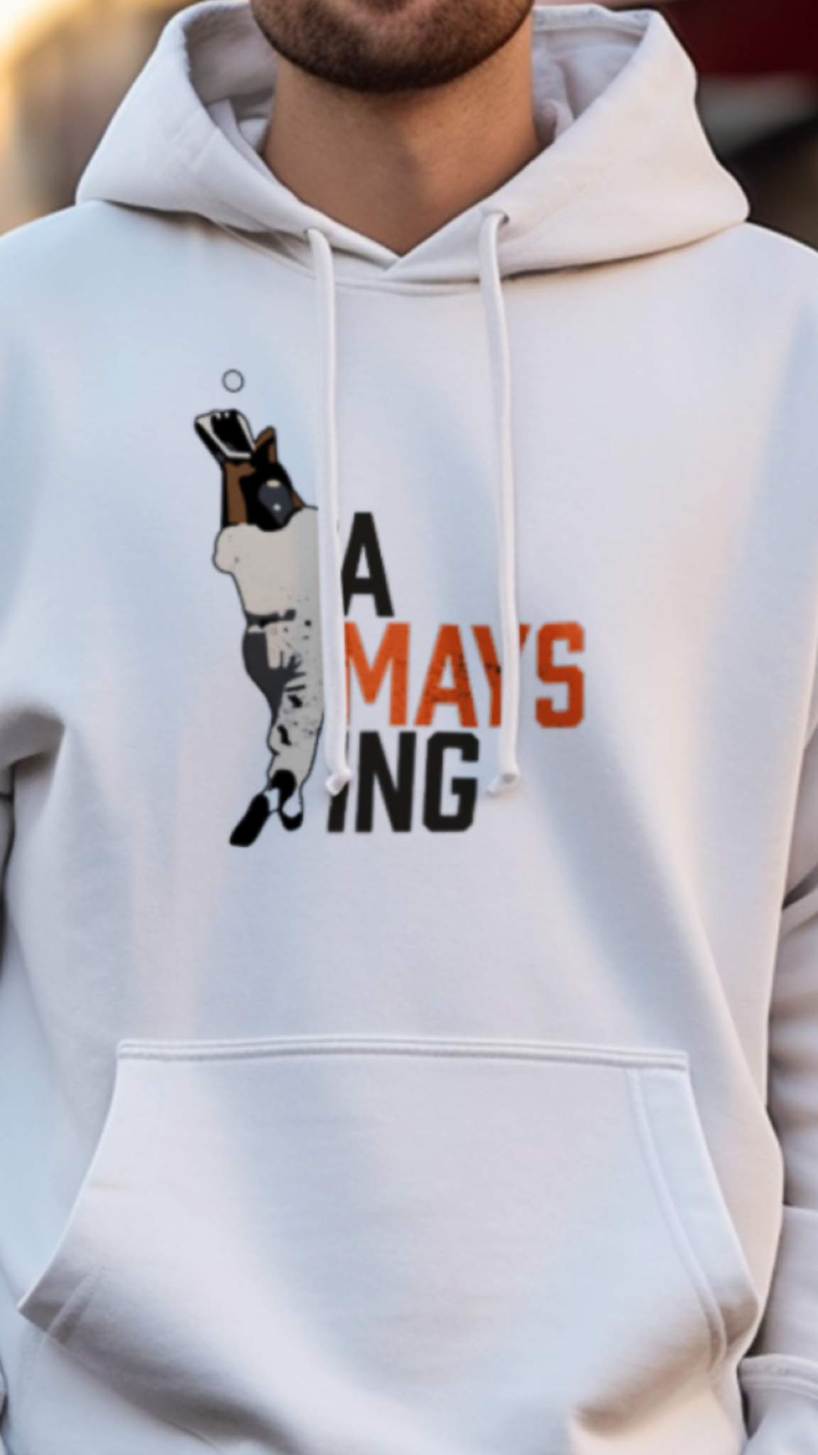 Man wearing a white hoodie with a graphic design on a street background