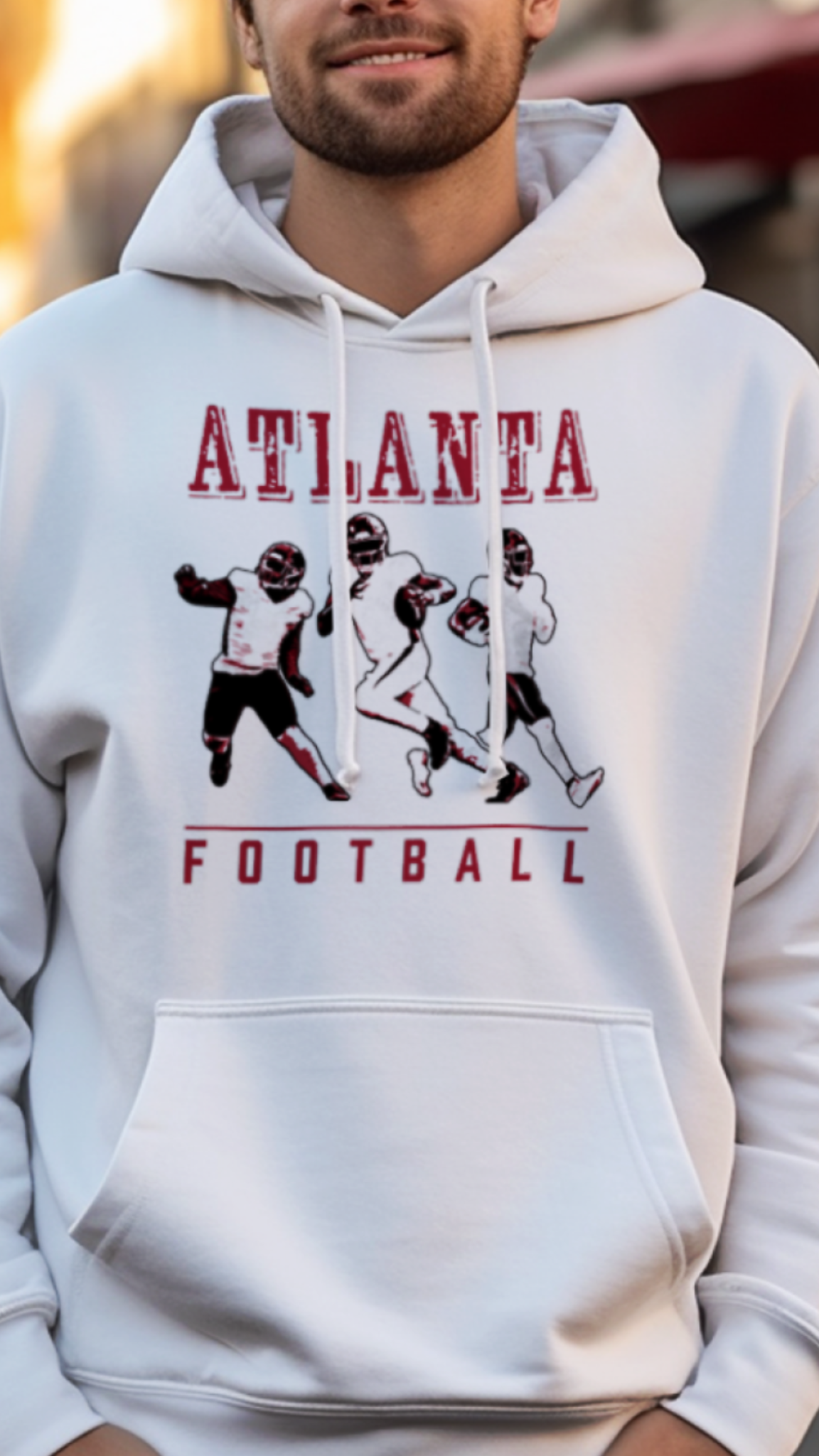 Man wearing a white hoodie with 'Atlanta Football' design on a street background