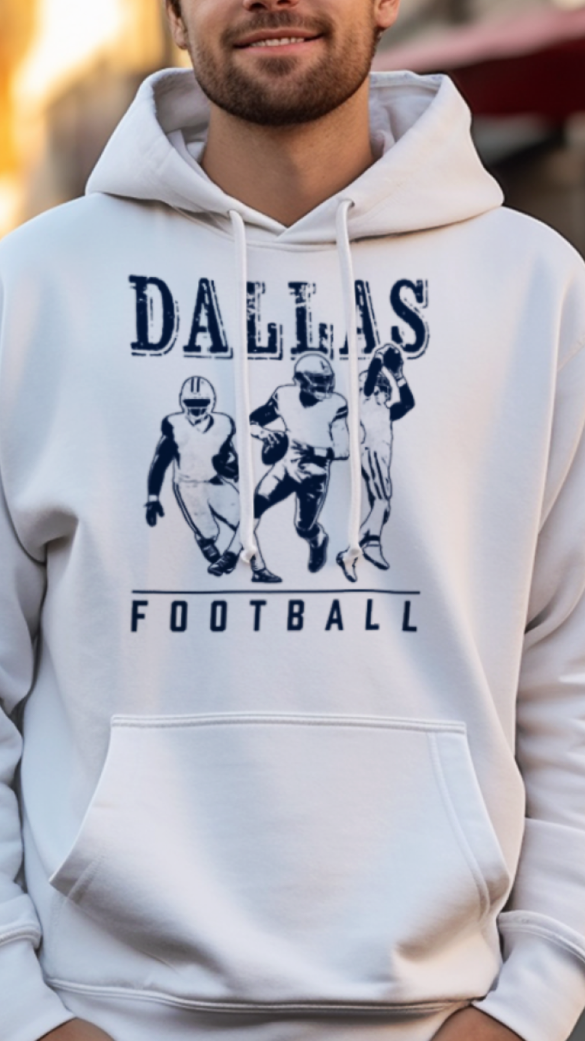 Man wearing a white hoodie with 'Dallas Football' text and graphics on a street background