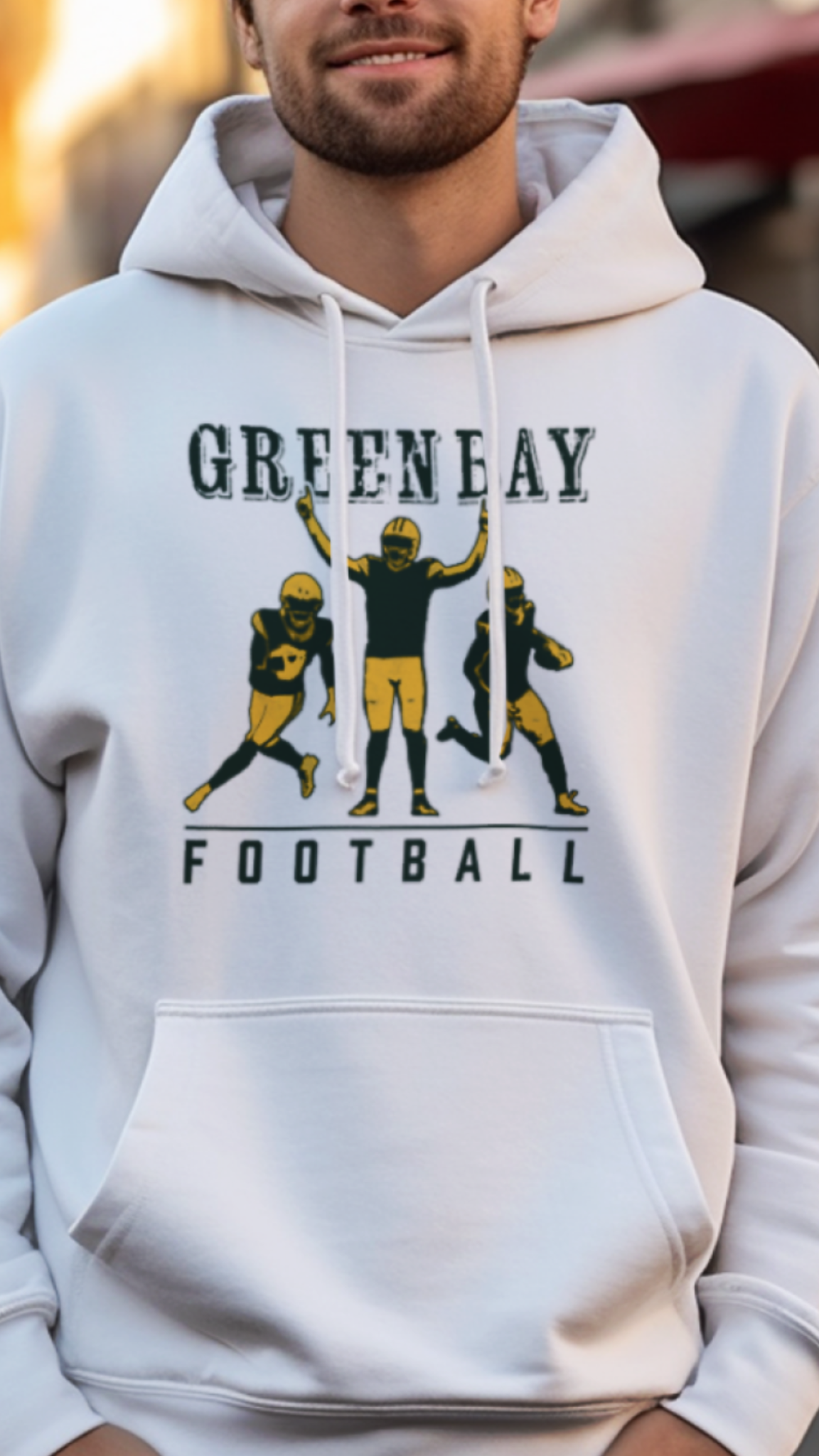 Man wearing a white hoodie with 'Greenbay Football' design on a street.