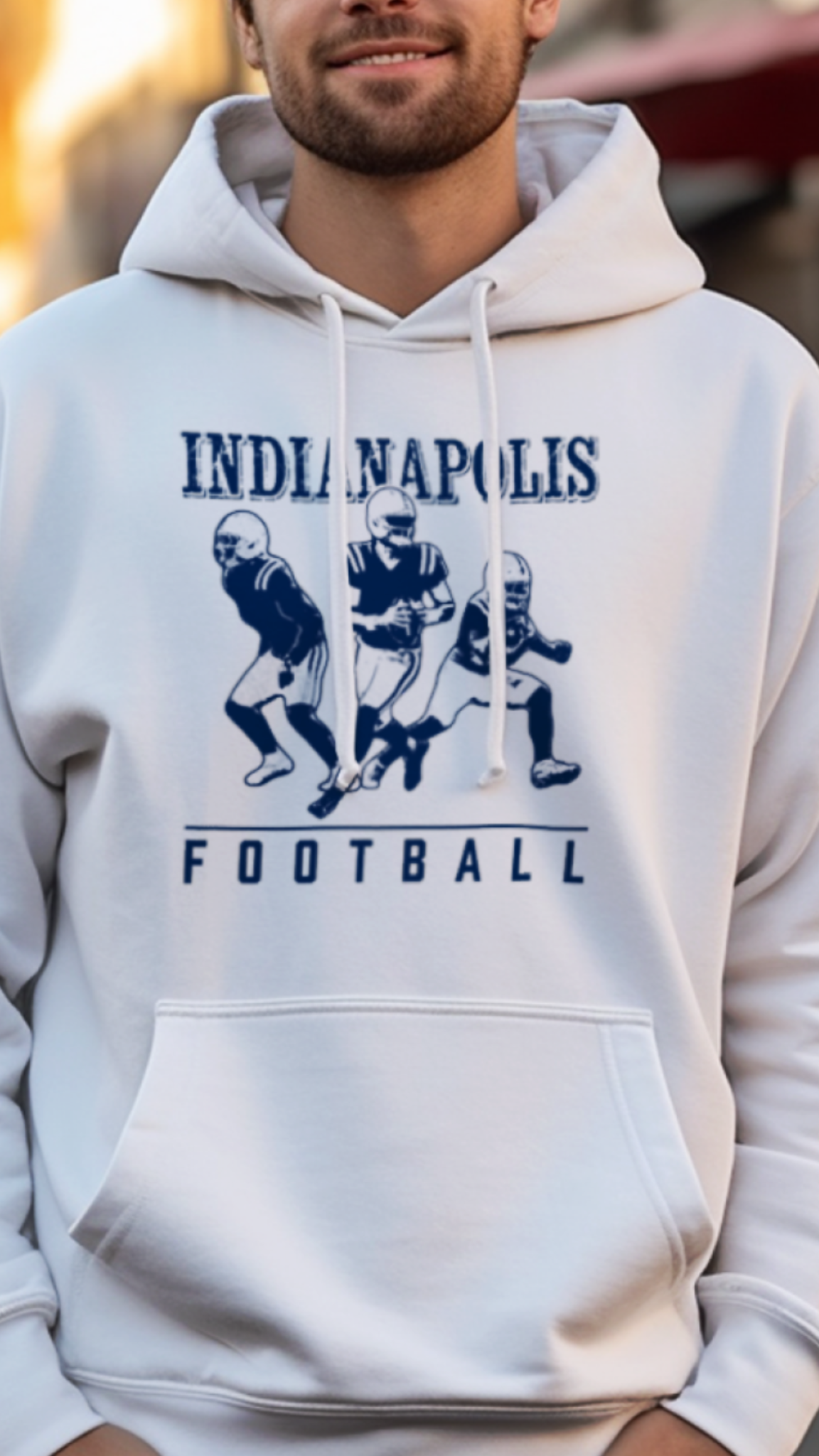 Man wearing a white hoodie with 'Indianapolis Football' design on a street background