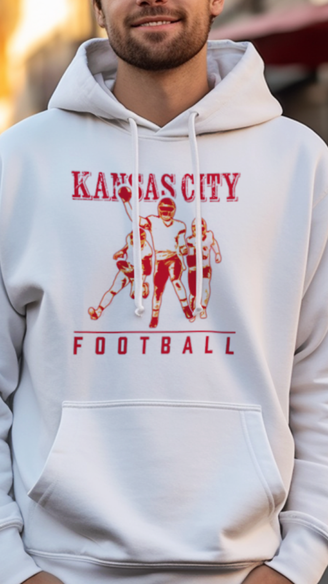 Man wearing a white hoodie with 'Kansas City Football' design on a street.