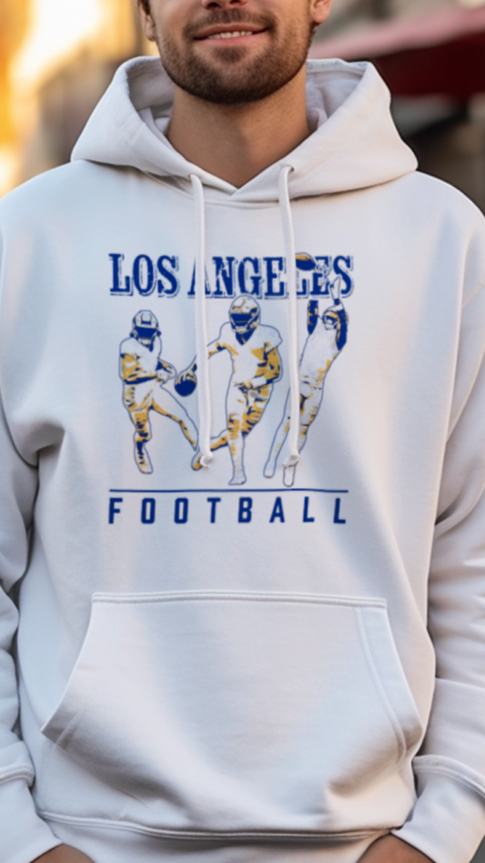 Man wearing a white hoodie with 'Los Angeles Football' design on a street.