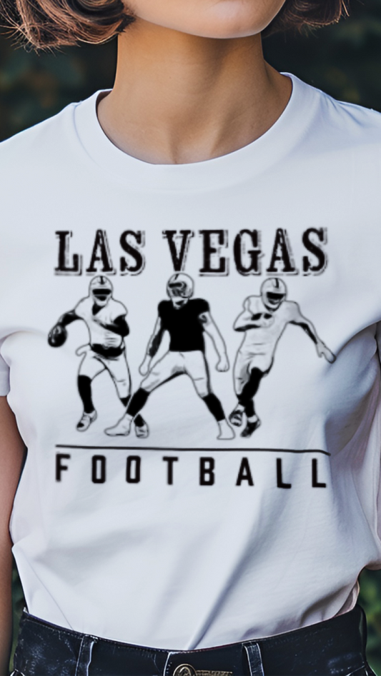 Person wearing a white t-shirt with 'Las Vegas Football' design in a garden setting