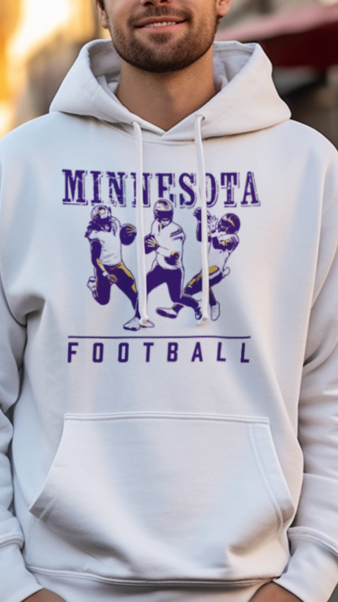 Man wearing a white hoodie with 'Minnesota Football' text and graphics on a street background