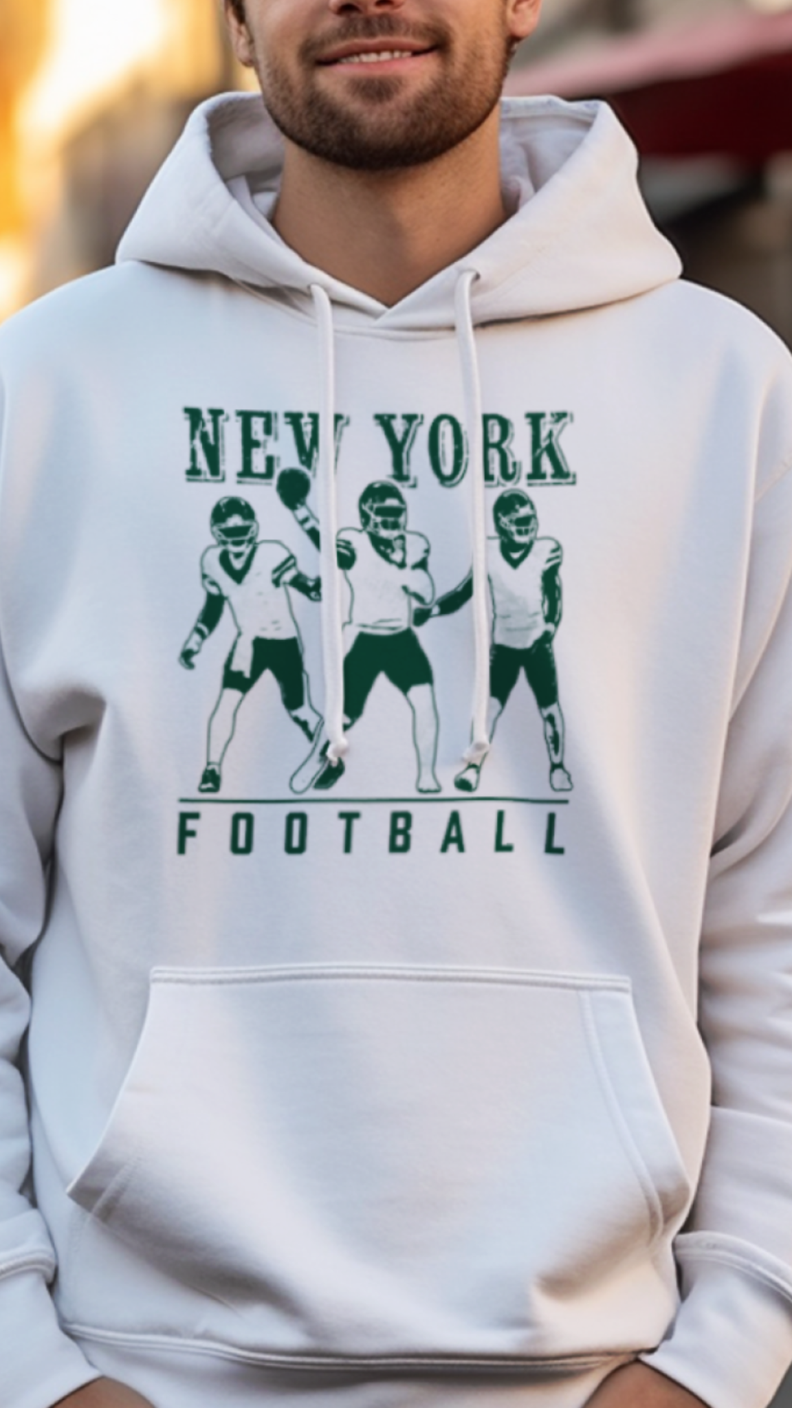 Person wearing a white hoodie with 'New York Football' design on a street.