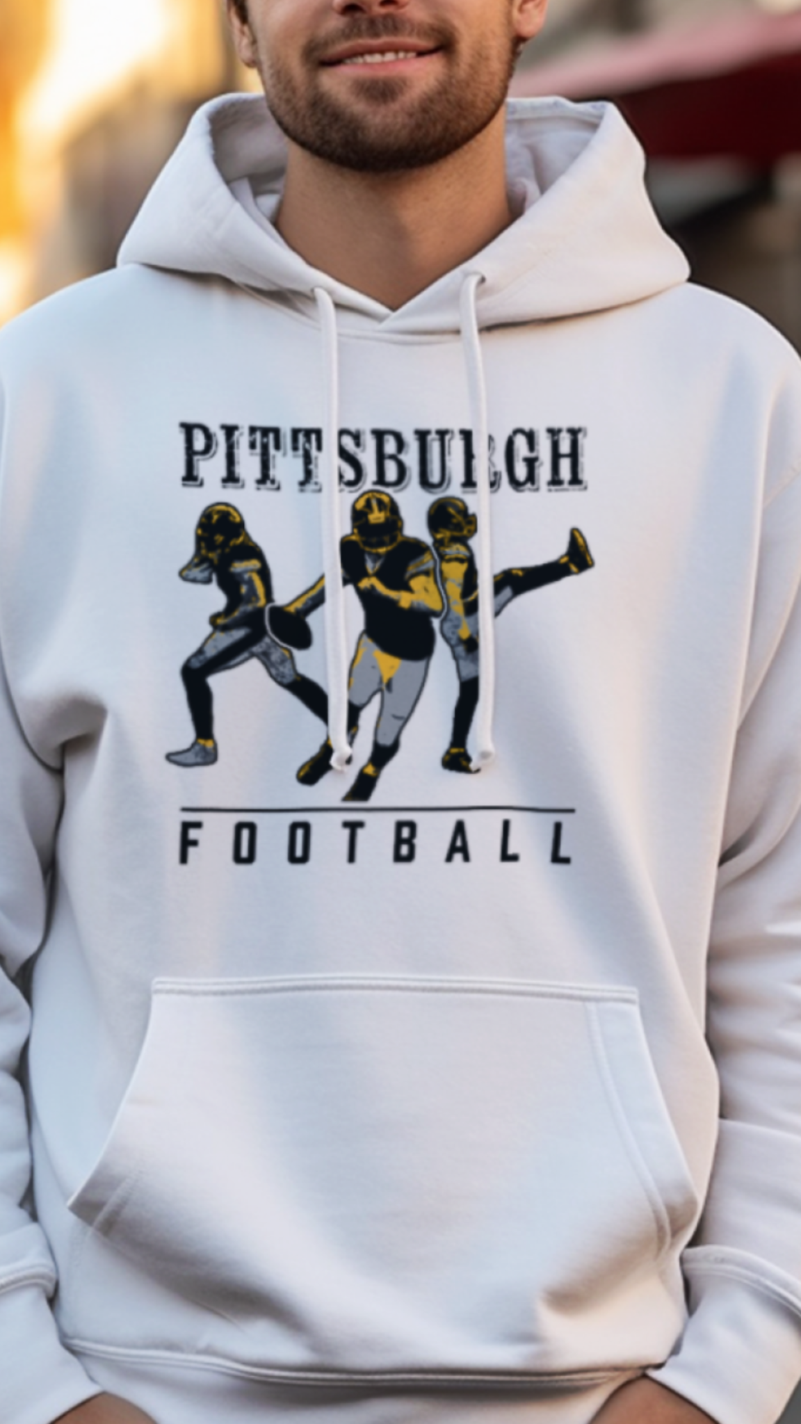 Person wearing a white hoodie with 'Pittsburgh Football' design on a city street.