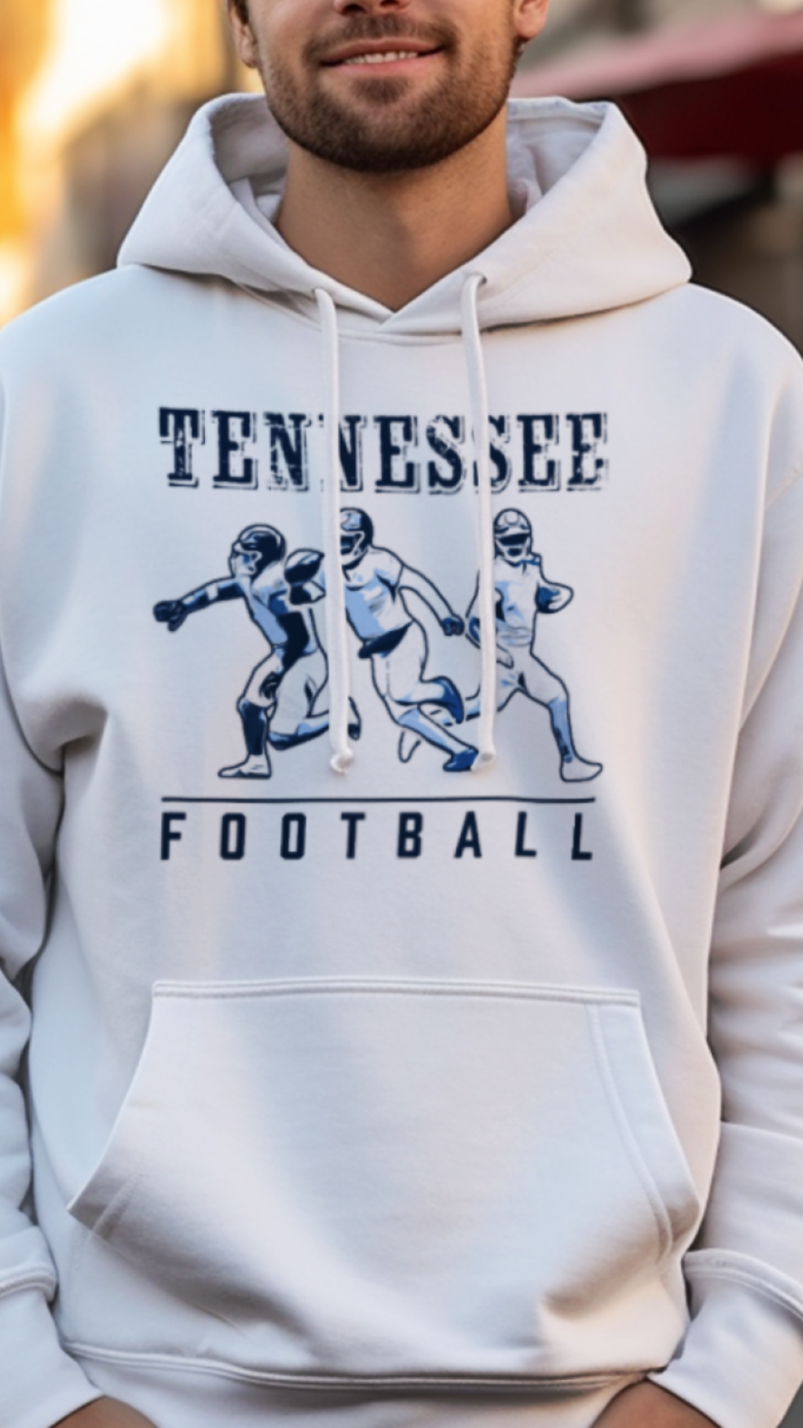 Man wearing a white hoodie with 'Tennessee Football' text and graphics on a street background